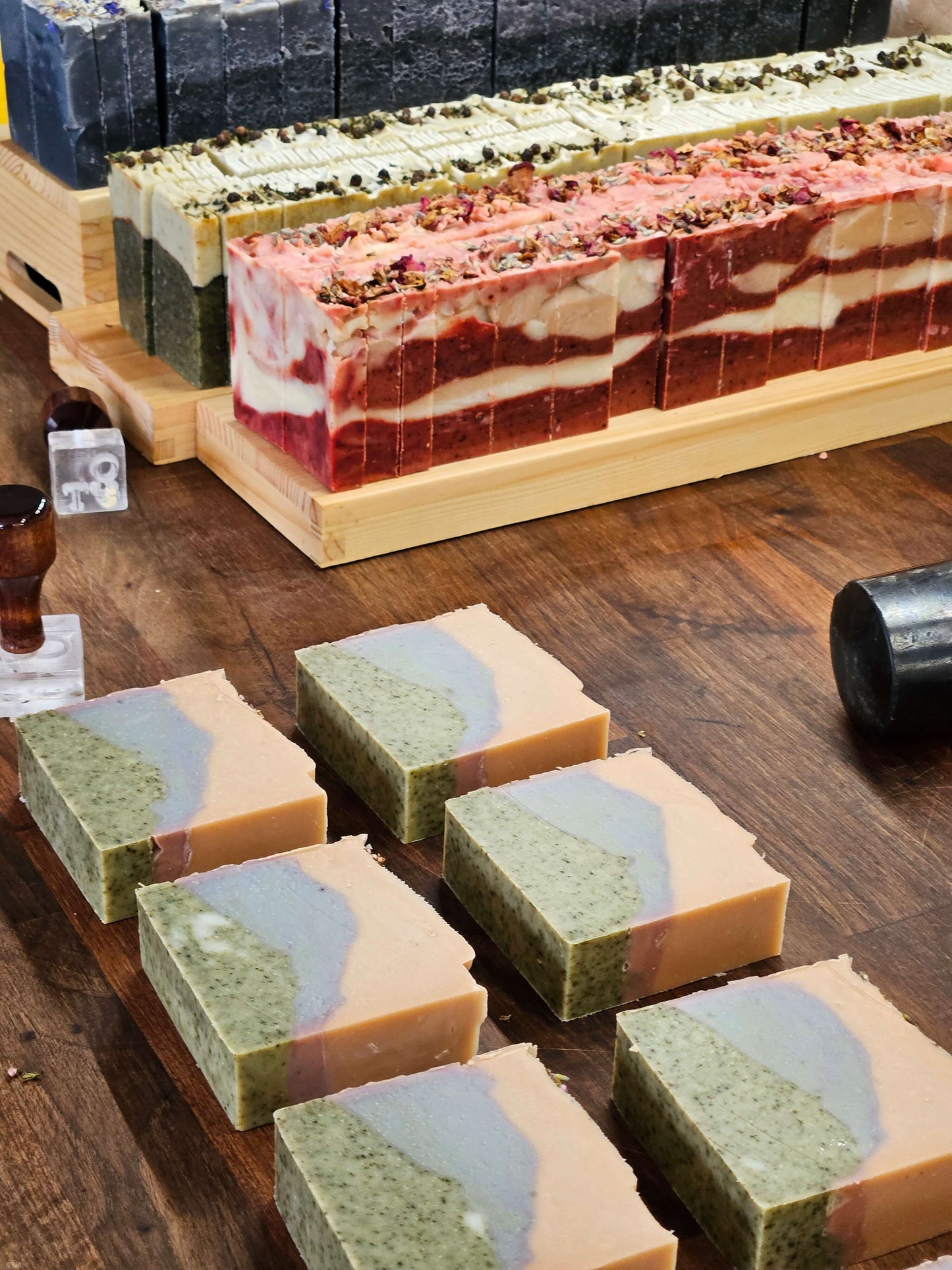 Freshly made soaps on worktop being stamped with o&t logo, heather, flora, fern and moss