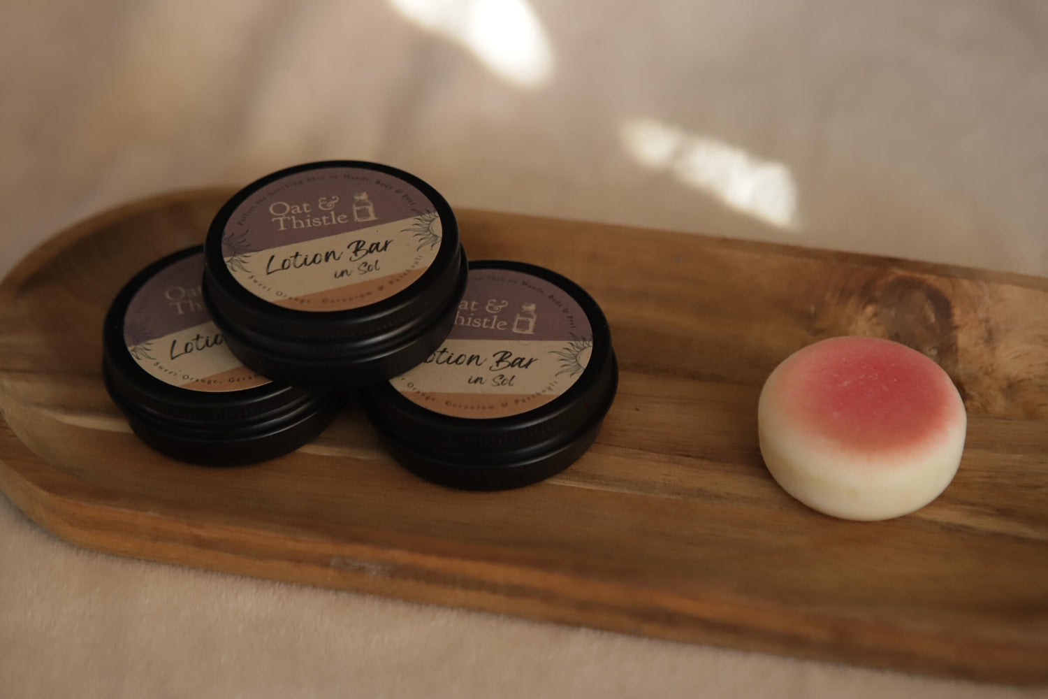 Pink sol lotion bar on wooden tray with black metal tin