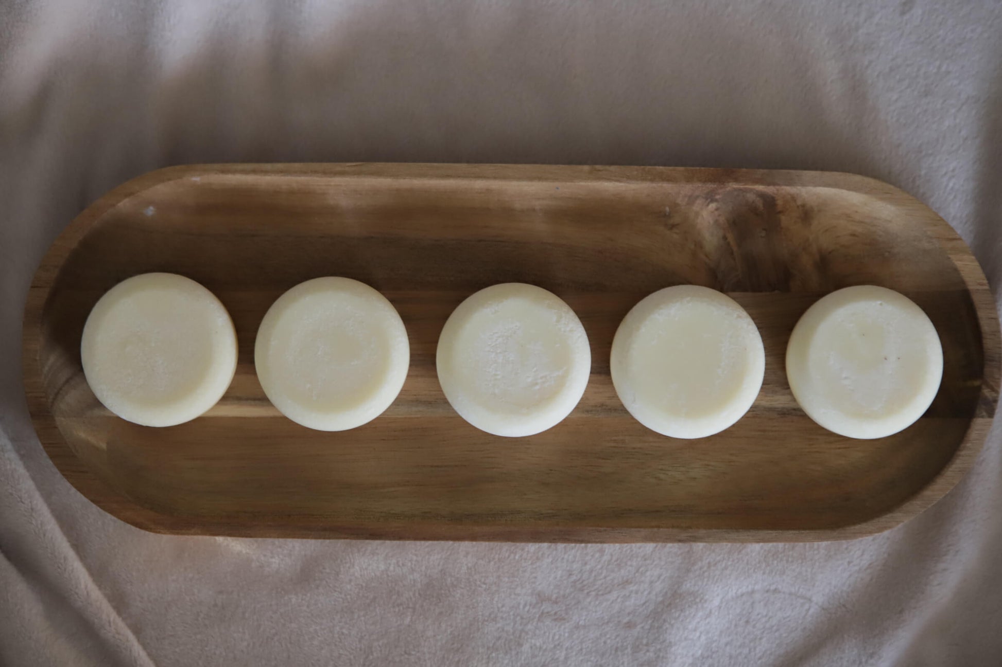 White nude lotion bars on wooden tray