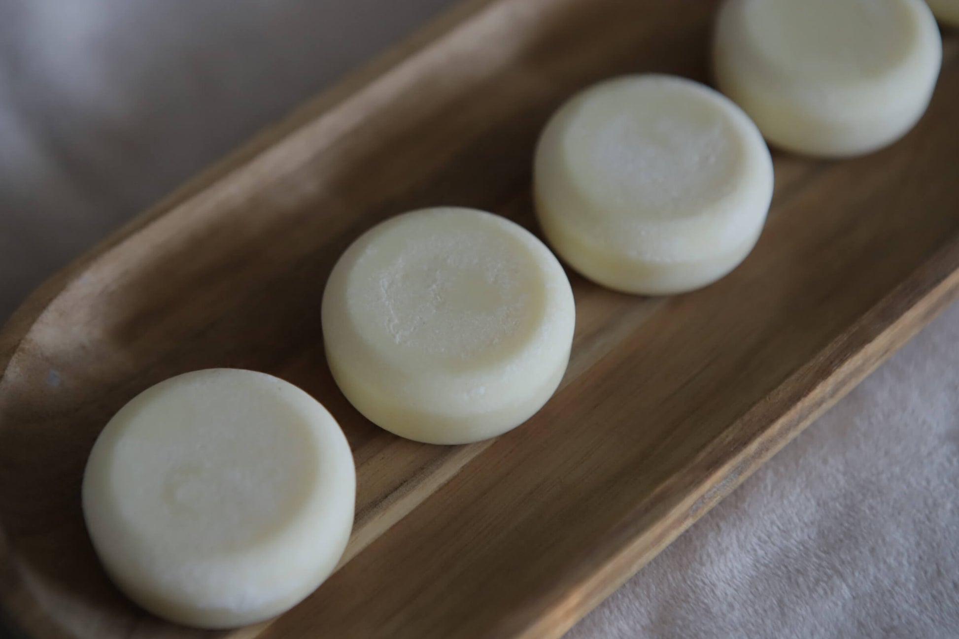white Nude lotion bars on a wooden tray