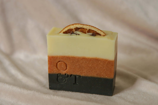 Spice soap bar, black orange creamy with striped colours, topped with an orange and cloves and stamped with the o&t logo