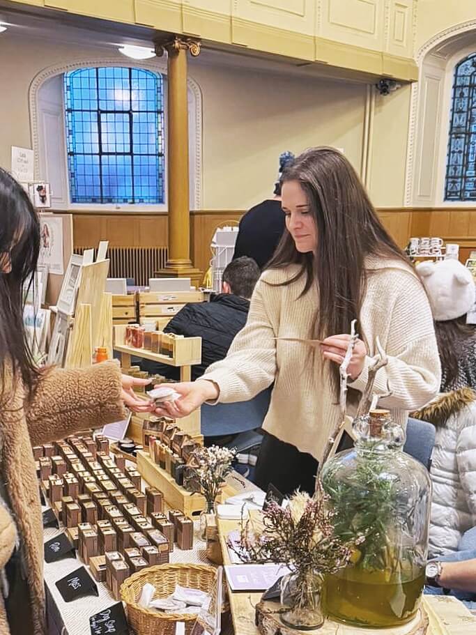 Anna (owner of O&T) at a market wrapping up a product for a customer